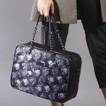 Handtasche in Hellblau, Grau und Schwarz aus Seide mit floralem Muster, getragen.