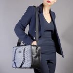 borsa a mano blu e nera in seta con stampa geometrica indossata