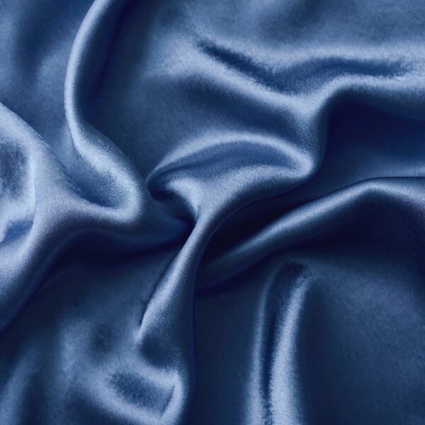 Silver silk background with a folds. Abstract texture of rippled silk surface