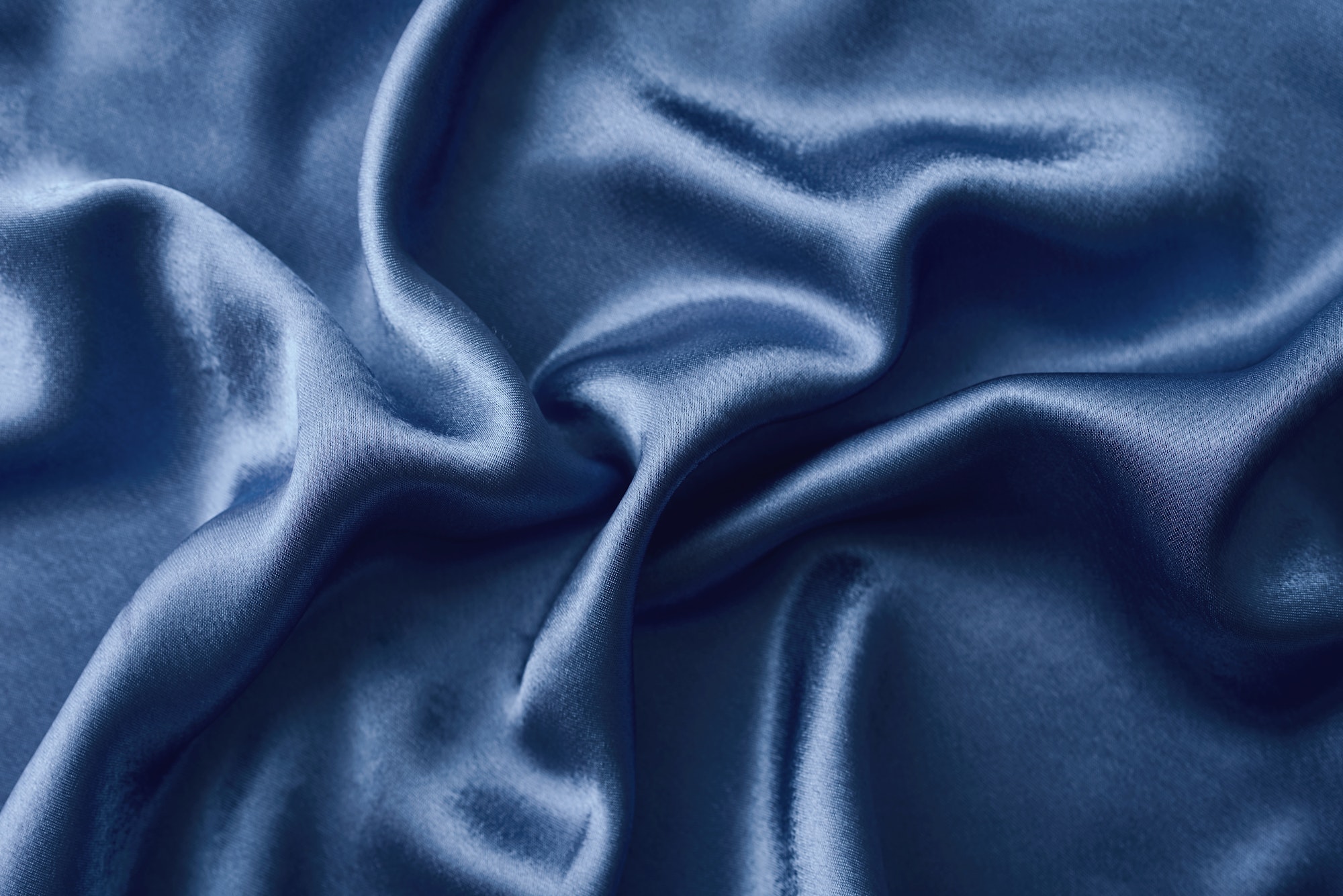 Silver silk background with a folds. Abstract texture of rippled silk surface
